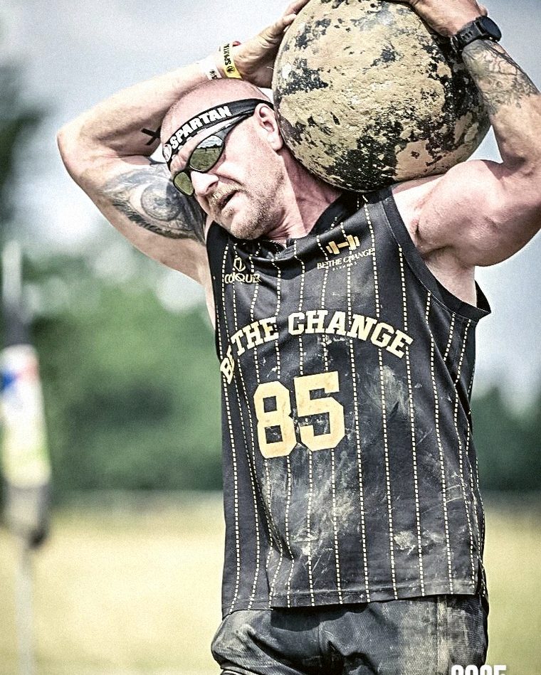 Julian Spiller carrying an atlas stone in Be The Change Fitness kit